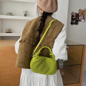Detailed view of the bright green textured bucket bag with woven handle and pleated finish