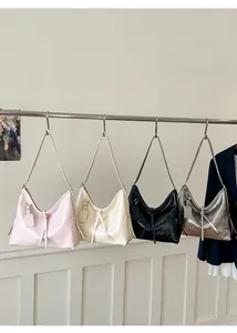 Close-up of hobo shoulder bags in pink, white, black, and silver with knotted detail