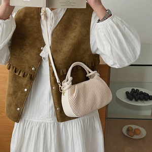 Close-up of cream pleated bucket bag with gold hardware and knot handle detail