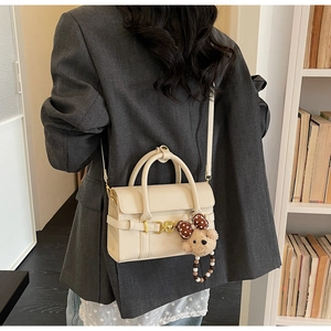 Cream white handbag with gold hardware and a cute plush bear charm with a polka dot bow