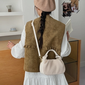 Detail of cream white bucket bag with pleated texture and adjustable strap on a model