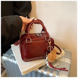 Macro shot of burgundy box-style handbag with fashion text and brown bear charm