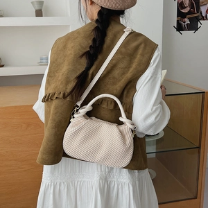 Detail of cream pleated bucket bag with twisted handle and adjustable strap