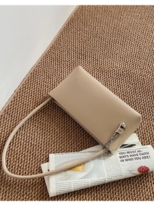 Detail of light beige leather shoulder bag featuring a silver crescent buckle on the flap