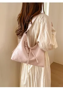 Detailed view of pink textured faux leather shoulder bag with decorative strap detail
