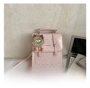 Detail of pink polka dot mini backpack with a brown plush monster charm and metal buckle