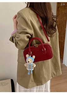 Detail of dark red vintage bowler bag in suede finish with a cute woven bear charm