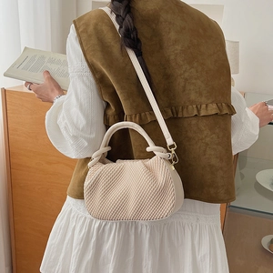 Detail view of cream bucket bag showing intricate pleated texture and gold hardware