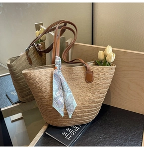 Detail of straw tote bag with brown leather straps and a blue patterned silk scarf accessory