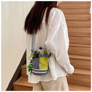 Detail of outdoor crossbody bottle bag with drawstring closure and green pompom charm