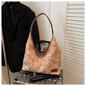 Close-up of floral tote bag with brown leather straps on a metallic suitcase