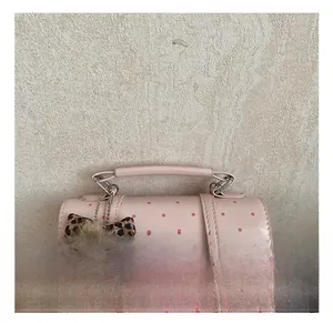 Detail of pink polka dot handbag featuring synthetic leather handle and plush bear charm