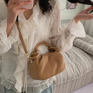 Detail of camel bucket bag with woven texture, golden hardware and adjustable strap