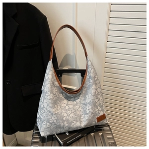 Detail of floral canvas tote bag with brown leather handles on silver luggage case