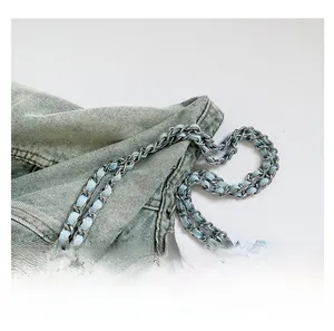 Close-up of a blue denim tote bag featuring a metal and fabric interwoven chain strap