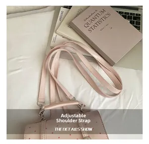 Detail of adjustable pink polka dot bag strap with polished silver metal buckle