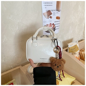 Detail of white leather mini crossbody bag with cute teddy bear charm and top handles