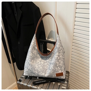 Detail of grey floral hobo tote bag with brown leather handles for travel use