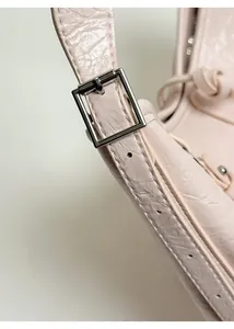 Detail of adjustable glossy crinkled leather shoulder strap with silver buckle on pink tote