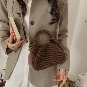Detail of dark brown woven bucket bag with smooth leather handles and gold metal hardware