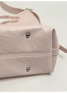 Close-up of a pink tote bag bottom with silver metal studs and reinforced base structure
