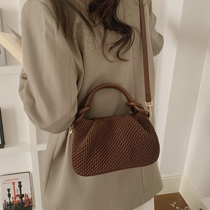 Macro detail of dark brown pleated texture and reinforced handle on a bucket bag