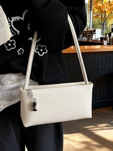 Minimalist off-white underarm bag with silver bean charm and faux leather shoulder strap