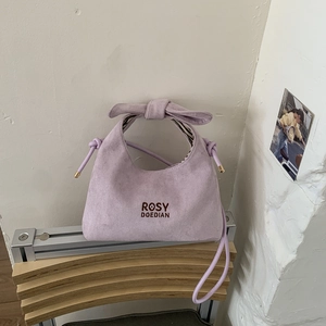 Detail of lavender suede handbag featuring side drawstrings and embroidered logo