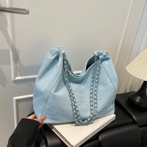 Détail du sac hobo bleu clair avec texture denim et bandoulière en chaîne argentée