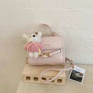 Detail of light pink PU leather square bag with golden lock and cute white bear charm