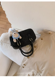 Détail du sac Boston noir en daim avec ferrures dorées et breloque ours en peluche