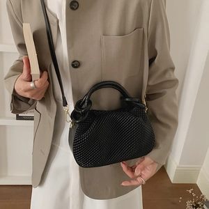 Detail view of woven leather bucket bag styled with an elegant khaki blazer and white dress