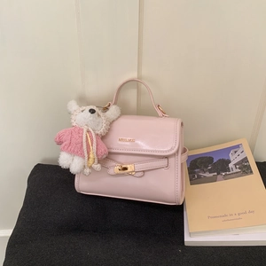 Close-up of pink leather handbag with gold MOHELI logo and cute teddy bear charm