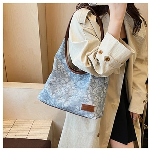 Close-up of floral canvas tote bag with brown leather strap and vintage logo patch