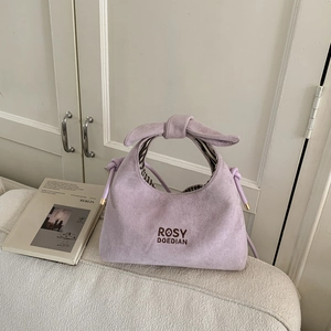 Detail of lavender suede dumpling bag with knot handle and brand embroidery