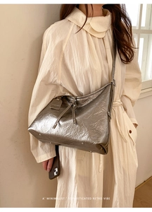 Detailed view of silver metallic tote bag with pleated texture on white shirt dress