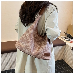 Side view of large pink floral canvas tote bag with brown leather trim on female model