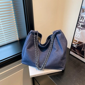 Gros plan d'un cabas en denim bleu foncé avec une bandoulière en chaîne tressée chic