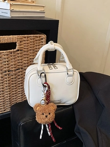 White textured mini square handbag with bear charm and double zipper closure in lifestyle setting