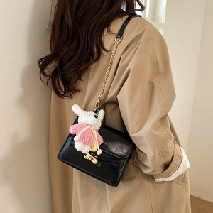 Detail of black leather crossbody bag with golden clasp and cute white bunny charm