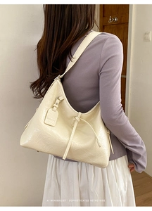 Detail of the glossy cream oil wax leather texture and logo charm on this hobo bag