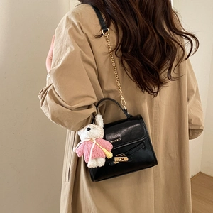 Detail of black crossbody bag with gold hardware and a cute white rabbit charm