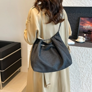 Détail du sac hobo en denim gris foncé avec une bandoulière en chaîne élégante