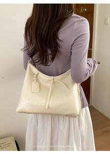 Detail view of cream tote bag with retro pleated PU leather texture and shoulder strap