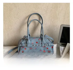 Close-up of denim Boston bag with red floral pattern and metallic belt buckle detail