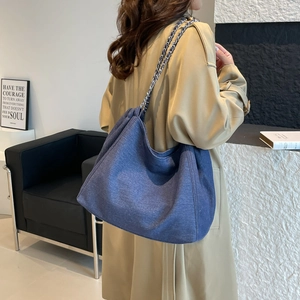 Détail d'un grand sac fourre-tout en toile bleue avec bandoulière chaîne sur un trench