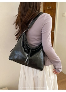 Close-up of black oil wax leather shoulder bag showing glossy texture and retro strap