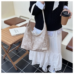 Detail view of floral canvas tote bag with white leather straps and textured pattern
