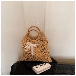 Detail of woven beach bag with wooden handles, lace bow and pearl chain ornament