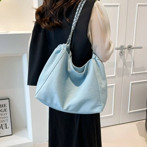 Sac hobo bleu clair avec bandoulière chaîne argentée porté à l'épaule de profil